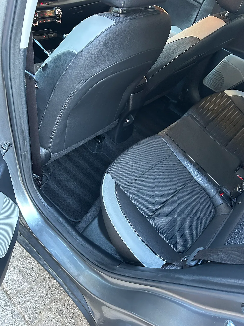 Interior view of a car showing the rear passenger seat and back of the front seat with black and gray upholstery.